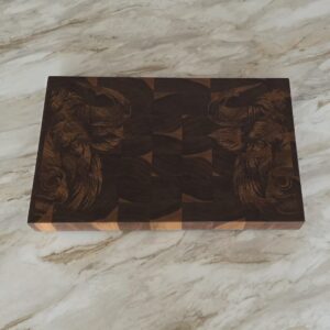 Detailed view of engraved bull head artwork on dark walnut checkered butcher block