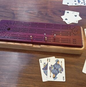 Padauk cribbage board track detail with brass pegs, handcrafted