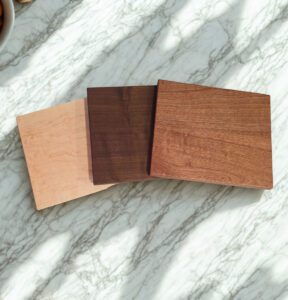 Three handcrafted kitchen boards in maple, walnut, and cherry wood on marble surface