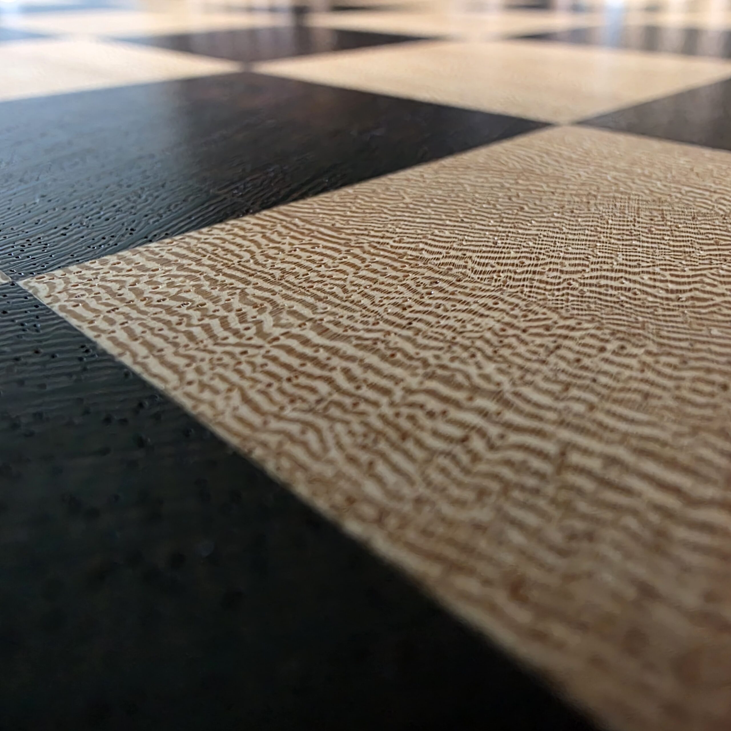 Close-up of the end-grain surface: rippled pale Lati squares against near-black pored wenge, showing true end grain