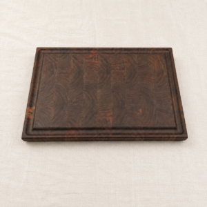 Custom walnut end grain cutting board made in Canada, with a routed juice groove, on linen